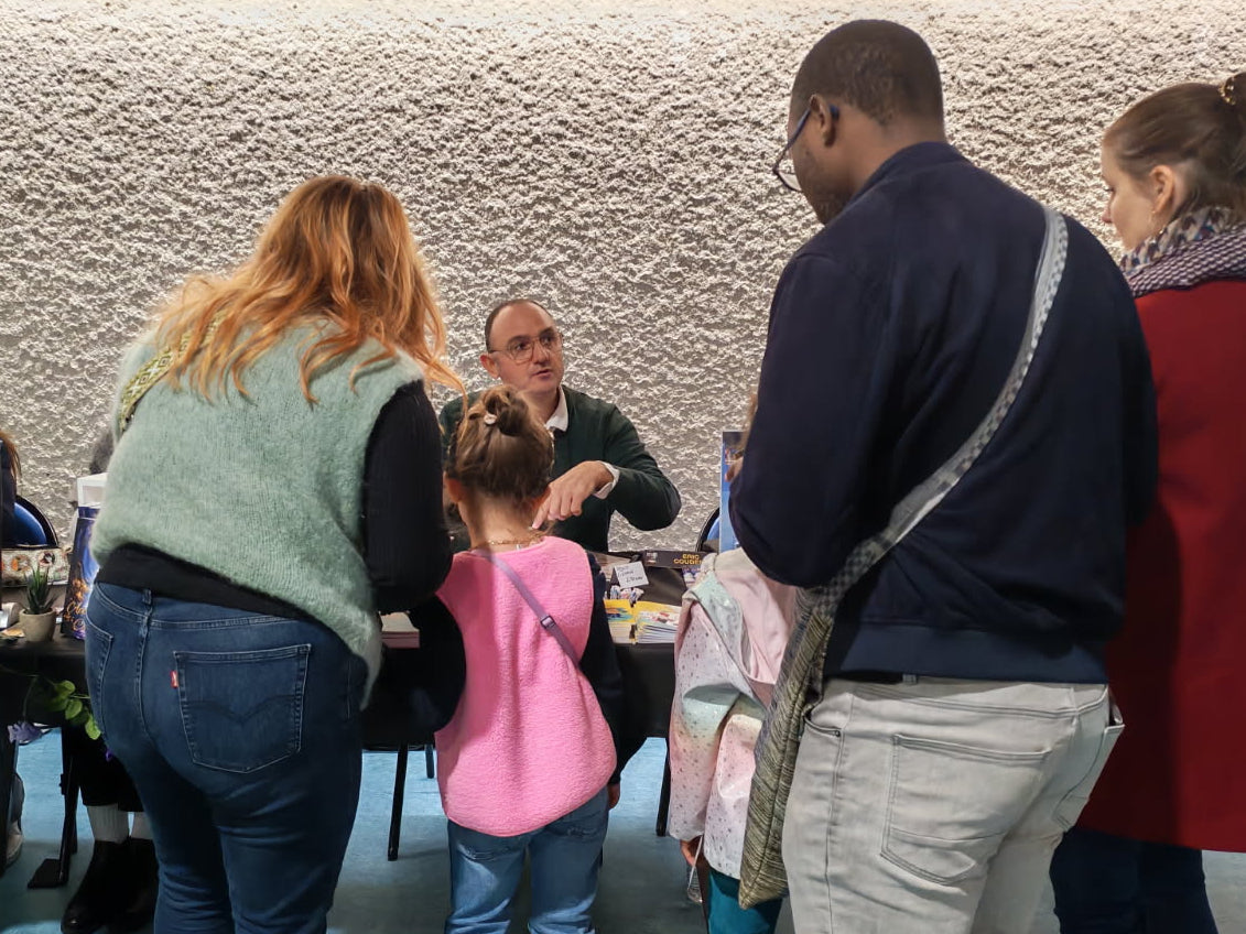 Eric Coudert en séance de dédicace, entouré d’une famille de lecteurs, échangeant et signant ses livres pour petits, moyens et grands.