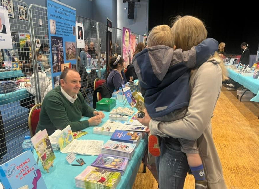 Eric Coudert en séance de dédicace au salon, échangeant avec ses jeunes lecteurs et signant ses livres de littérature jeunesse.